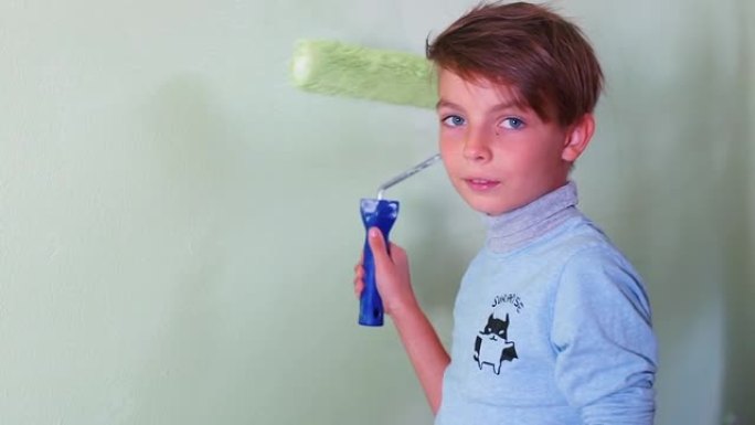 青少年表现出良好的手势，并开始用滚筒粉刷墙壁。