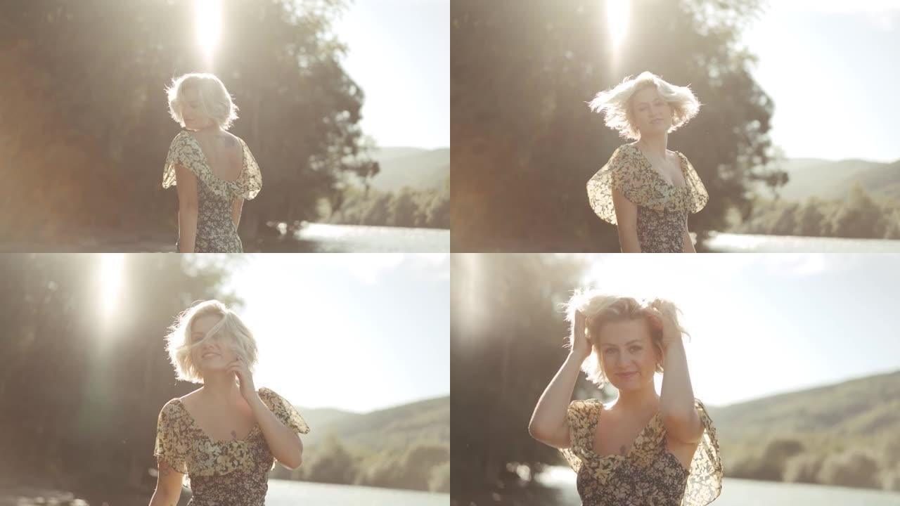 美丽的金发女孩在河边阳光明媚的日子里用相机调情
