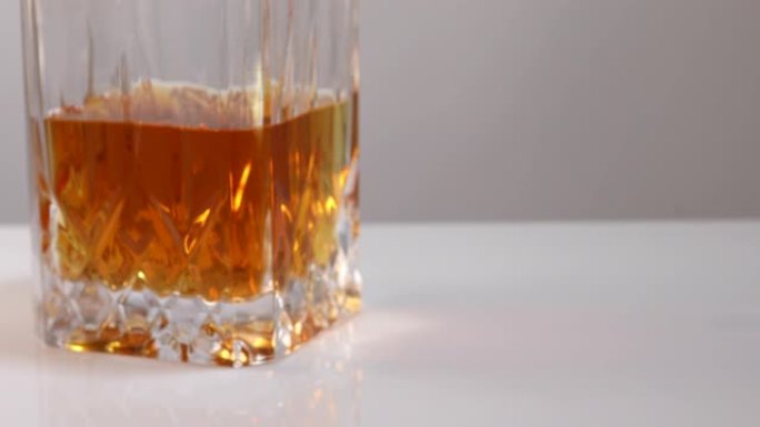 雄性手拿一杯威士忌或白兰地加冰，一秒钟后将空杯子放在适当的位置