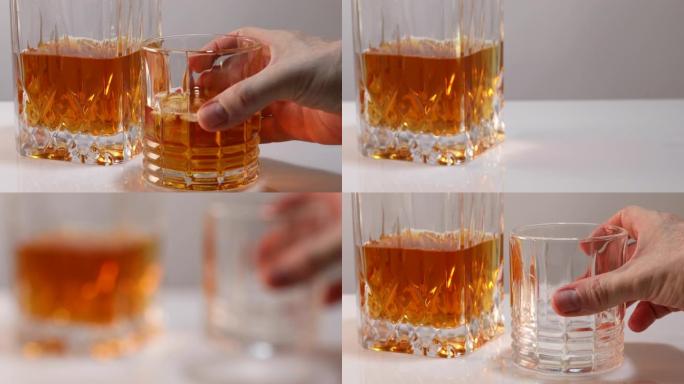 雄性手拿一杯威士忌或白兰地加冰，一秒钟后将空杯子放在适当的位置