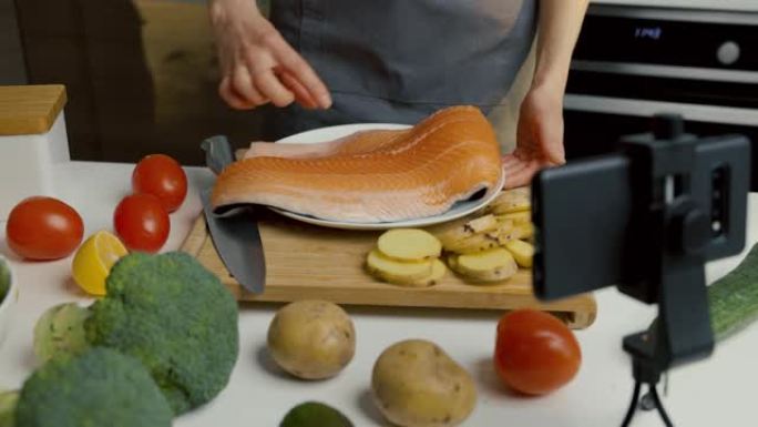 用手机摄像头在家庭厨房录制视频的食物视频记录器。展示鲑鱼准备食谱