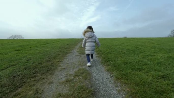 年轻女孩在阴天的冬季乡村跑步