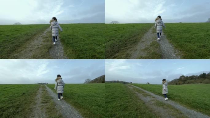 年轻女孩在阴天的冬季乡村跑步