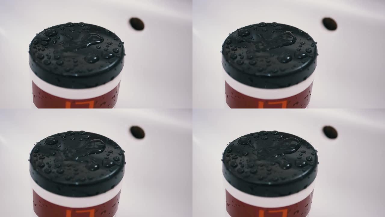 水滴从水龙头慢慢落下，喷在塑料盖的黑色表面上