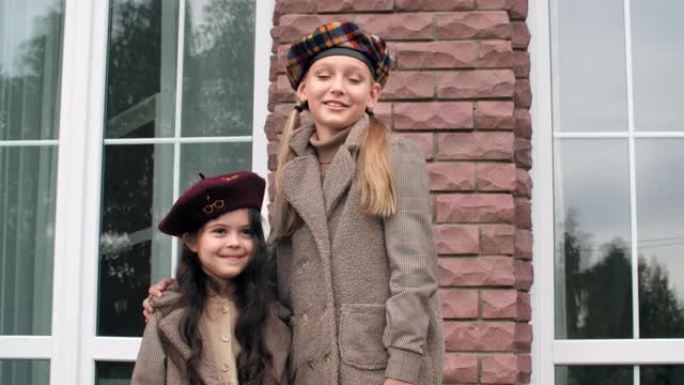 两个穿着贝雷帽的可爱的微笑女孩站在户外