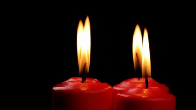 旋转四支红色蜡烛燃烧的火在黑色背景上缓慢旋转