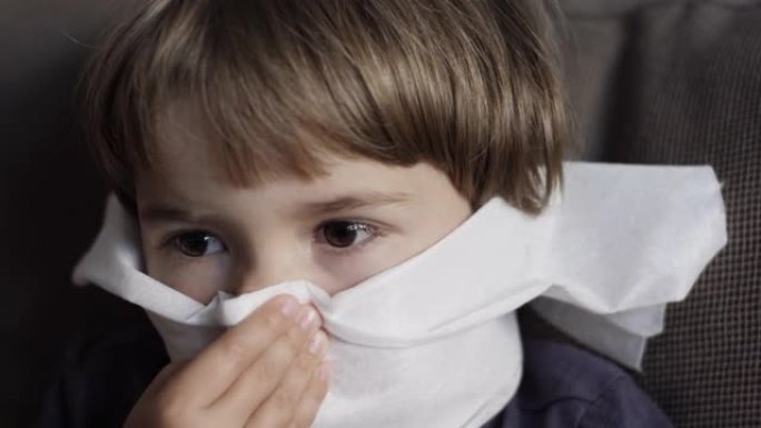不健康的生病男孩的肖像与餐巾关闭她的鼻子从过敏或鼻炎。不幸的生病的孩子从流鼻涕和打喷嚏和擤鼻涕。儿童