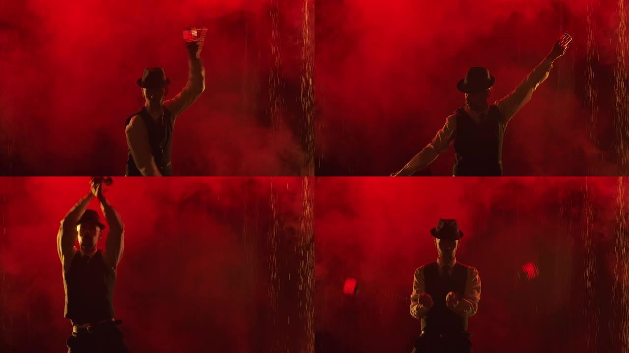 在黑暗的工作室里，在雨水下迷人的火与光表演。男子在红色烟熏工作室背景上旋转发光的发光二极管手榴弹。特