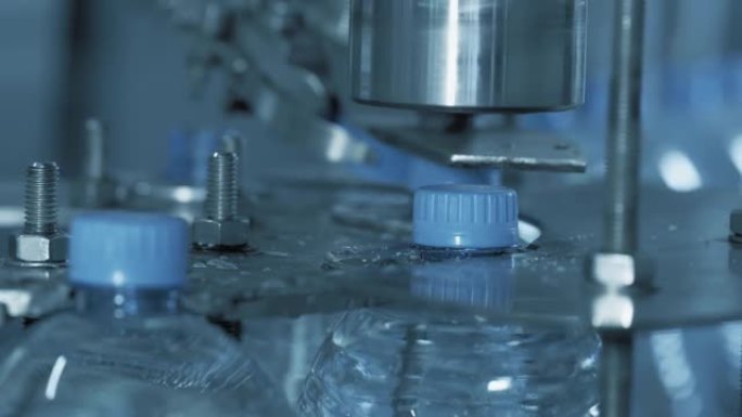 自动装置旋转瓶盖。自动化生产线，用于生产塑料瓶中的清洁水。打开干净的水瓶。
