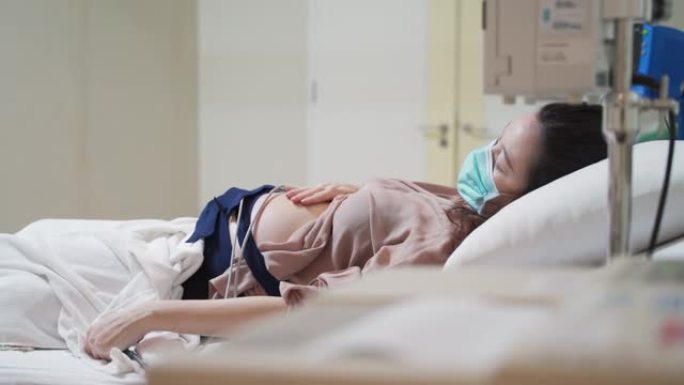 亚洲孕妇担心产前超声扫描。女性佩戴婴儿胎儿监护仪腰带在怀孕期间感到抑郁。