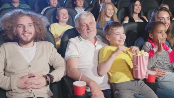 有孩子跪在地上的父母在电影院拍手。