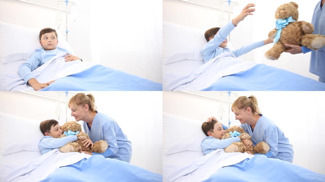 微笑的护士照顾一个躺在医院病床上的孩子，给他一只泰迪熊，使他感到惊讶
