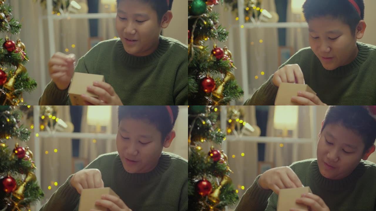 快乐的亚洲男孩穿着绿色毛衣打开礼品盒，配有圣诞装饰品，节日概念。