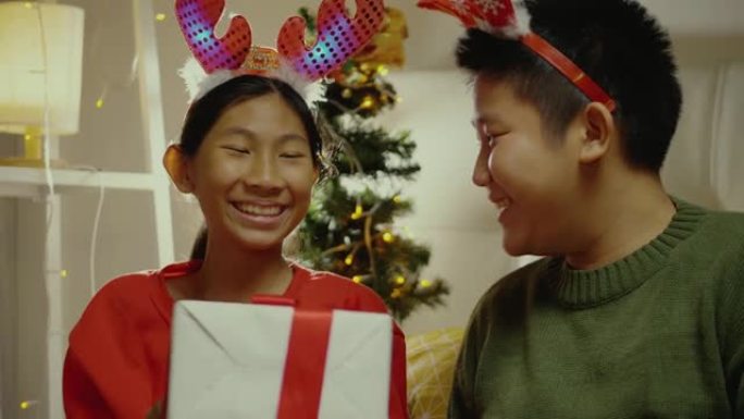 快乐的亚洲男孩在家里给妹妹送礼品盒，圣诞装饰品背景，生活方式概念。