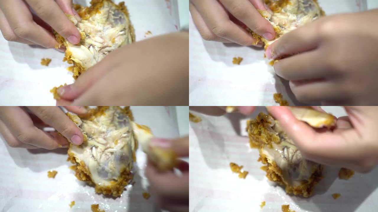 一个小孩在快餐店吃炸鸡。用手把鸡撕开。看过去。