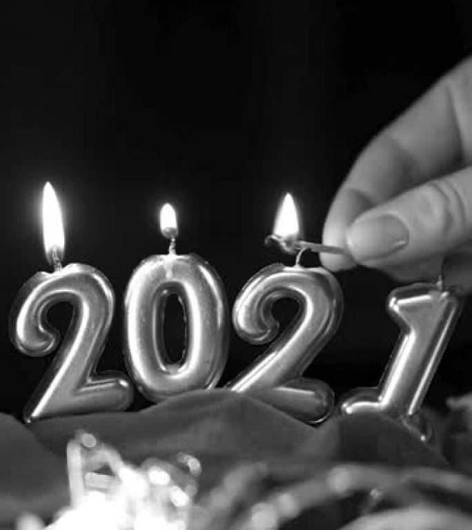 手灯2021年形式的蜡烛。垂直黑白视频。黑暗背景上的金色燃烧蜡烛。新2021年快乐庆典
