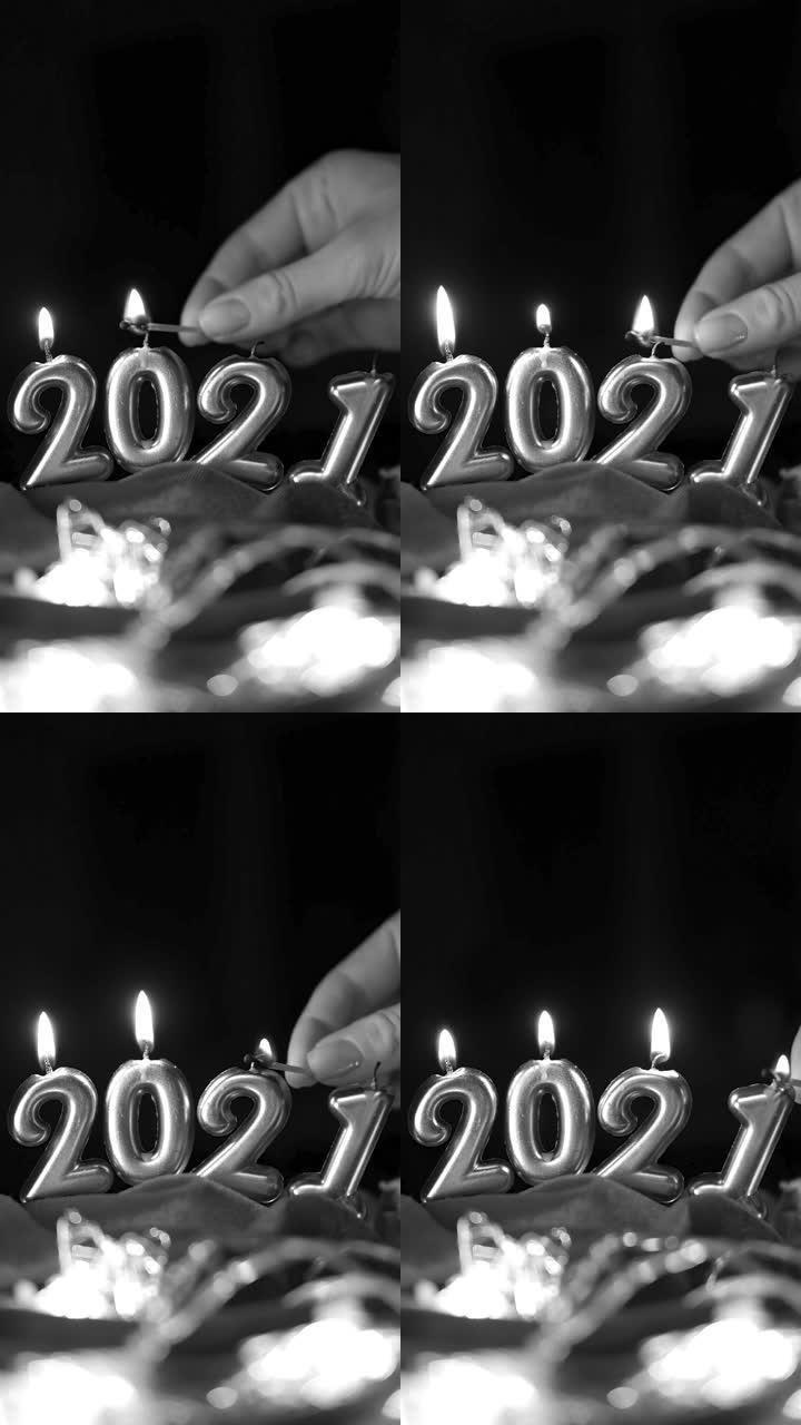 手灯2021年形式的蜡烛。垂直黑白视频。黑暗背景上的金色燃烧蜡烛。新2021年快乐庆典