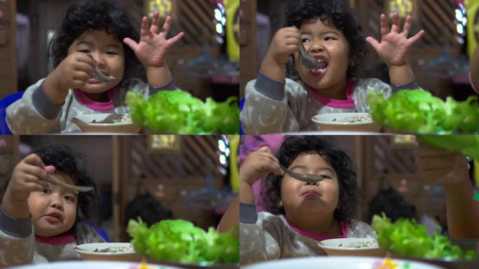 快乐的女孩用勺子吃美味的食物