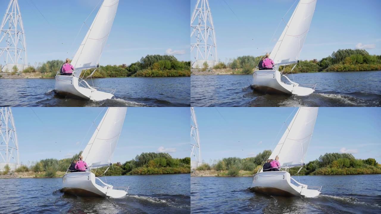 在河上的帆船赛期间，白色帆船沿着岸边和缆车的支撑冲过。慢速
