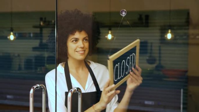 微笑的女商人在玻璃门上贴上打开的标志。
