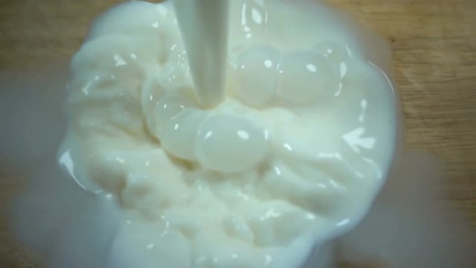 牛奶以慢动作倒入透明的碗中。