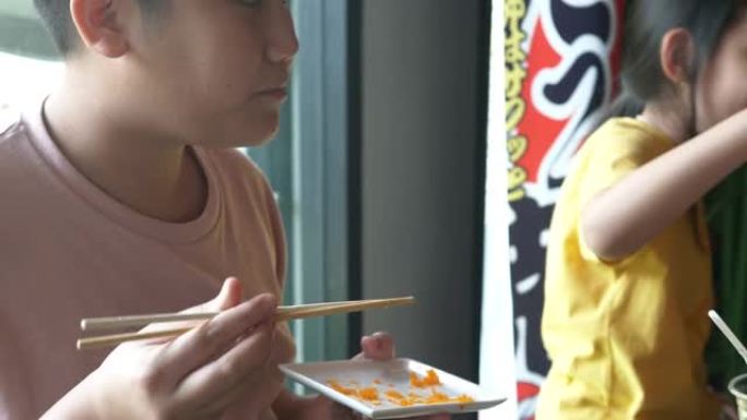 快乐的亚洲男孩在托盘上舔虾蛋寿司，生活方式理念。