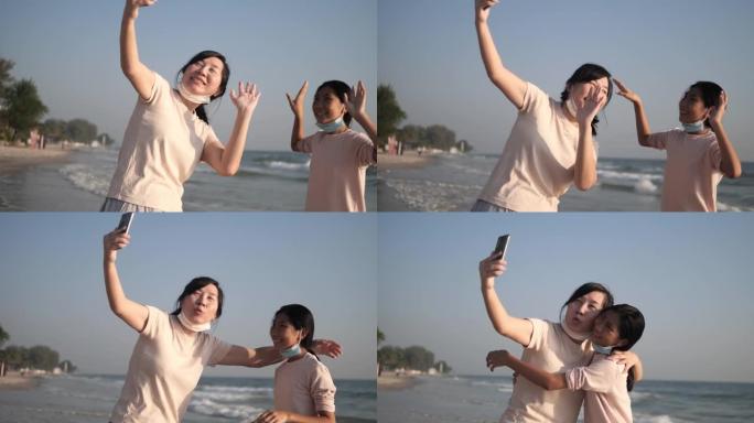 快乐的亚洲母亲和她的孩子在假期，科技概念早上在海滩上通过智能手机与家人拍照自拍或视频通话。