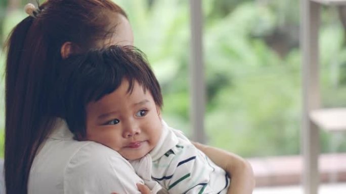 亚洲妈妈在家里的客厅抱着宝贝儿子。