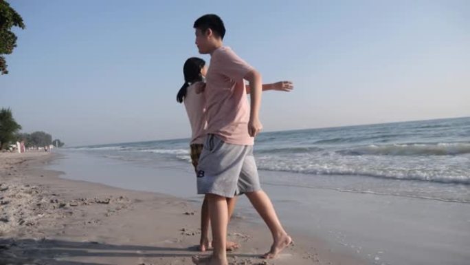 快乐的亚洲儿童在泰国华欣度假期间早上在海滩上跳舞。