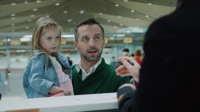 父亲手上害羞可爱的小女孩从登机处拿机票 ..机场航站楼。在红色相机上拍摄的电影。