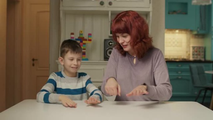 自闭症治疗师和自闭症孩子玩手指游戏。自闭症的男生在家和妈妈一起学习。自闭症儿童学会集中注意力和协调。