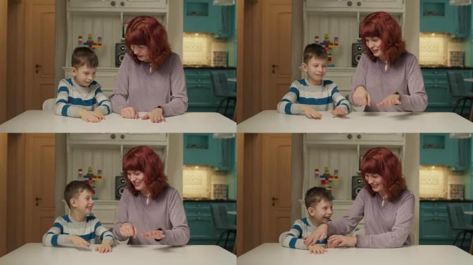 自闭症治疗师和自闭症孩子玩手指游戏。自闭症的男生在家和妈妈一起学习。自闭症儿童学会集中注意力和协调。