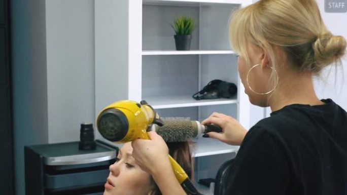 美容师在客厅给新发型后吹干女人的头发