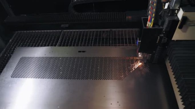 钣金激光切割机。顶视图。现代数控光纤激光器机器正在金属板上切割图案。切割过程中，明亮的燃烧火花从激光
