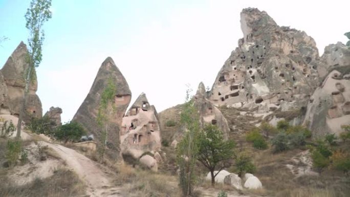 在Uchisar cave city旅行时，手持低角度视图，是古老的卡帕多西亚乡村景观，有种群形成，