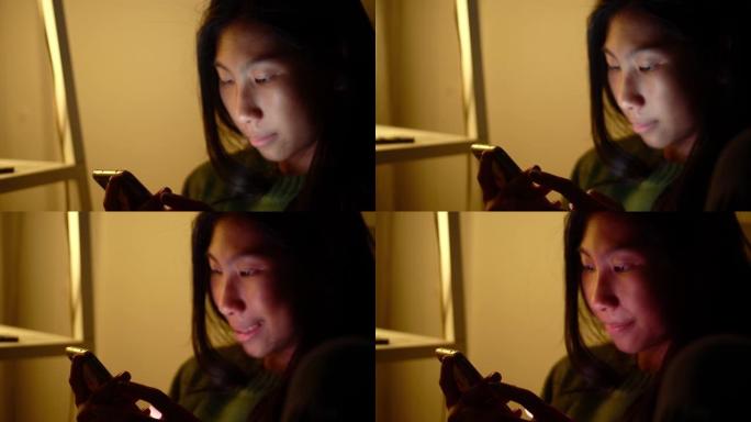 快乐的亚洲女孩坐在沙发上看YouTube剪辑，家里有灯灯，生活方式的概念。