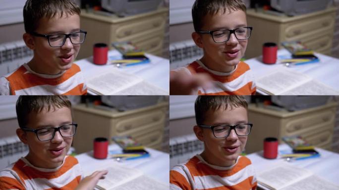 戴眼镜的聪明男孩微笑并谈论他在家里读的书。阅读
