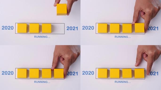 用手将木块放入进度条中运行快乐的新2020年2021年。新年快乐概念。