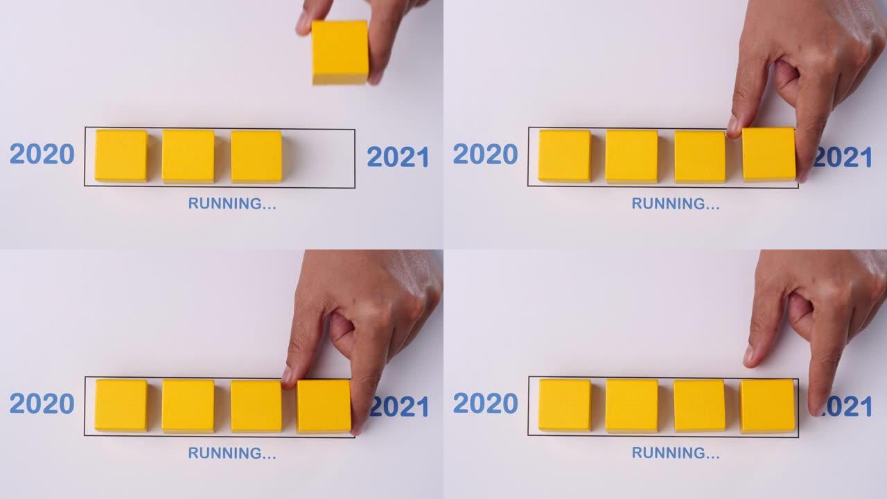 用手将木块放入进度条中运行快乐的新2020年2021年。新年快乐概念。