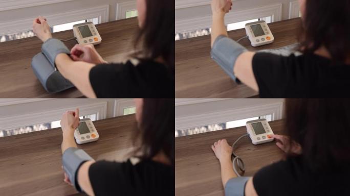 成年妇女在家中在自动血压机上检查血压
