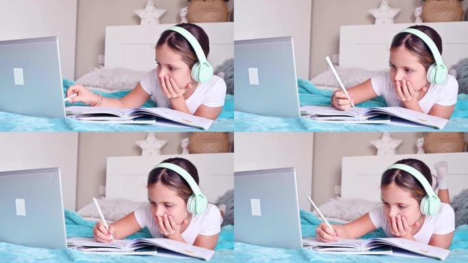 在线课程。一个小女孩，一个戴着耳机的女学生，带着课本，在电脑上上课。检疫时期家庭教育的新版本，cov