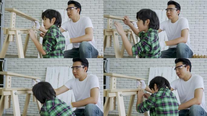 亚洲父子用小零件组装木制家具。小男孩帮他父亲组装一个桌架。