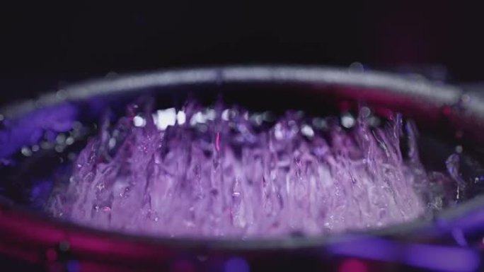 强大的声音扬声器在蓝色霓虹灯下投掷粉末的抽象概念。权力音乐。摇摇欲坠的扬声器在霓虹灯中抛掷液态水。录