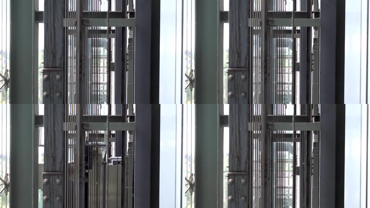 两部玻璃电梯在一栋现代化建筑中上下而上。钢绳上的特写镜头。