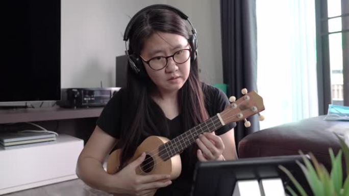 通过互联网智能手机学习夏威夷四弦琴的亚洲女性。