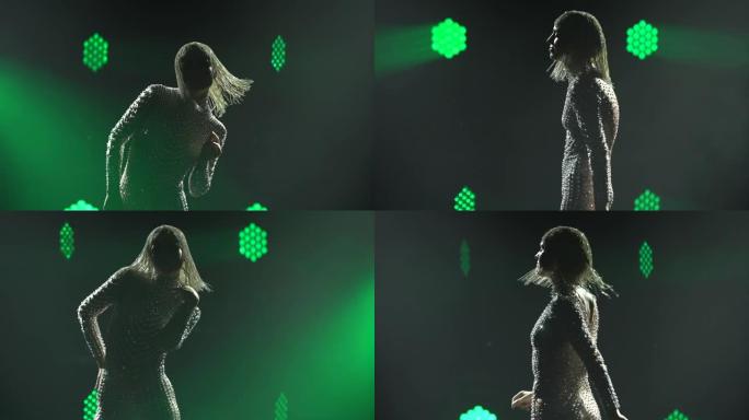 穿着闪亮服装和头饰的女舞者的剪影在绿色关注中心的舞台上热情地跳舞。特写