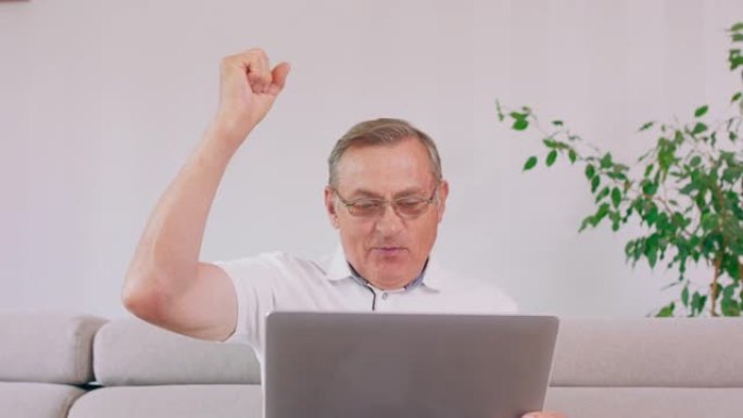 一位老人带着笔记本电脑在阅读好消息时欢呼雀跃