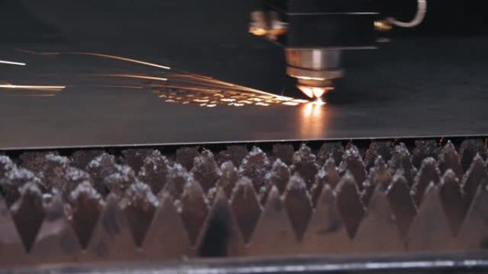 钣金激光切割机。特写。现代数控光纤激光器机器正在金属板上切割图案。切割过程中，明亮的燃烧火花从激光束