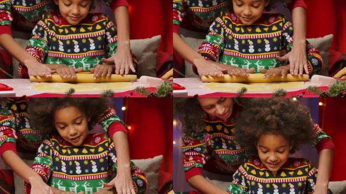 非裔美国妈妈和小女儿穿着明亮的节日毛衣，把面团卷在一起做自制饼干。快乐全家福，新年庆祝概念。特写