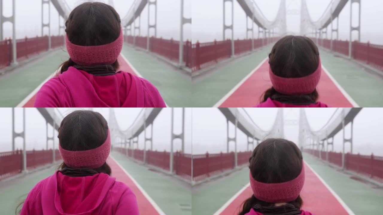 年轻胖乎乎的高加索女孩在桥上奔跑。后退射击。慢动作。紫色套装